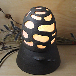 A glowing japanese toro style lamp in the shape of a morel mushroom
