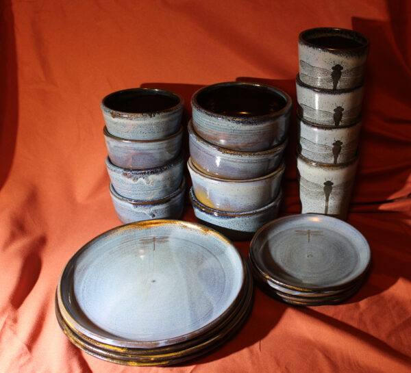 A set of ocean blue dishes, some of which have dragonflies engraved on them